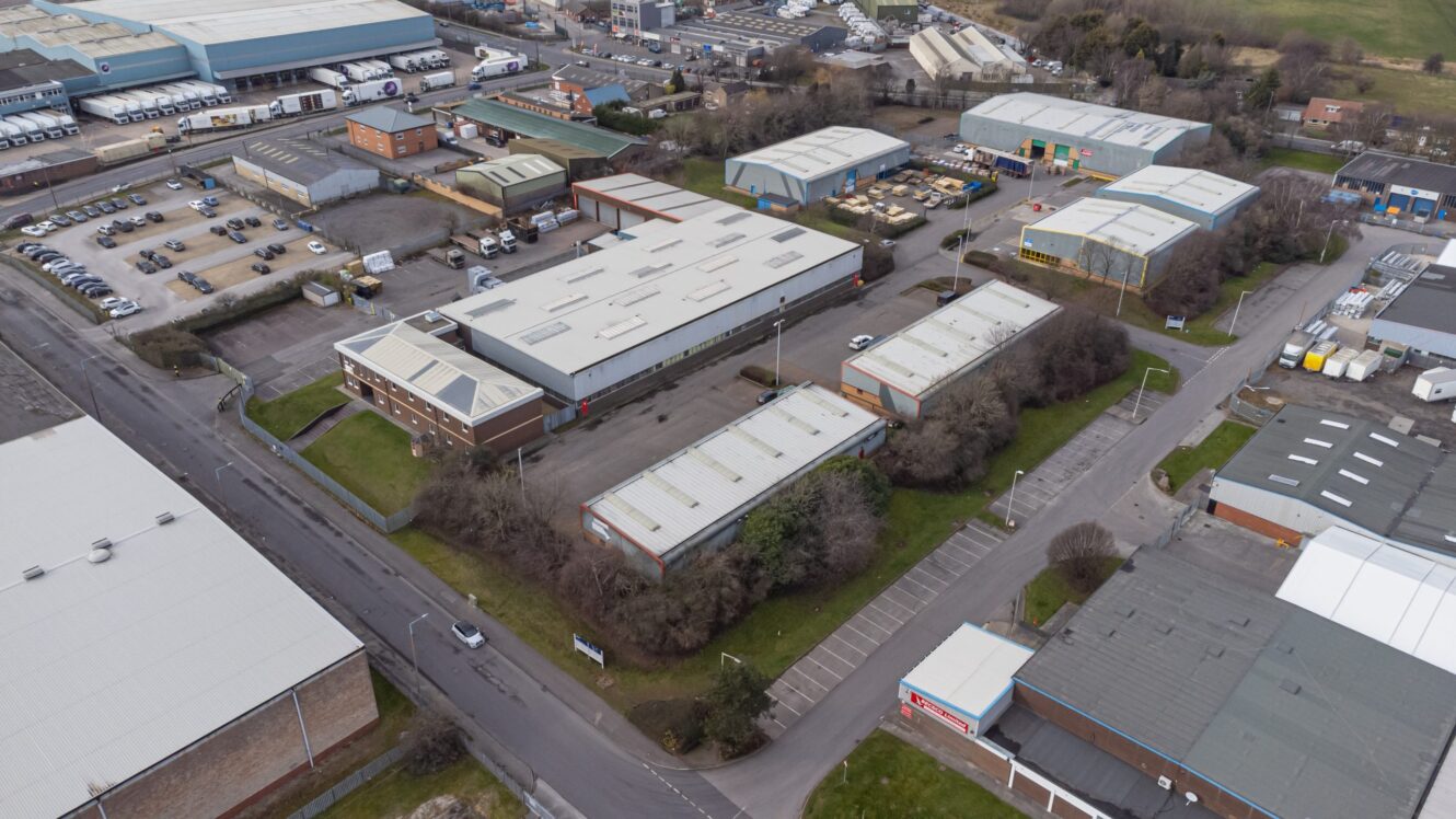 Aerial view of an industrial estate with multiple warehouses, office buildings, parking lots, and surrounding roads.
