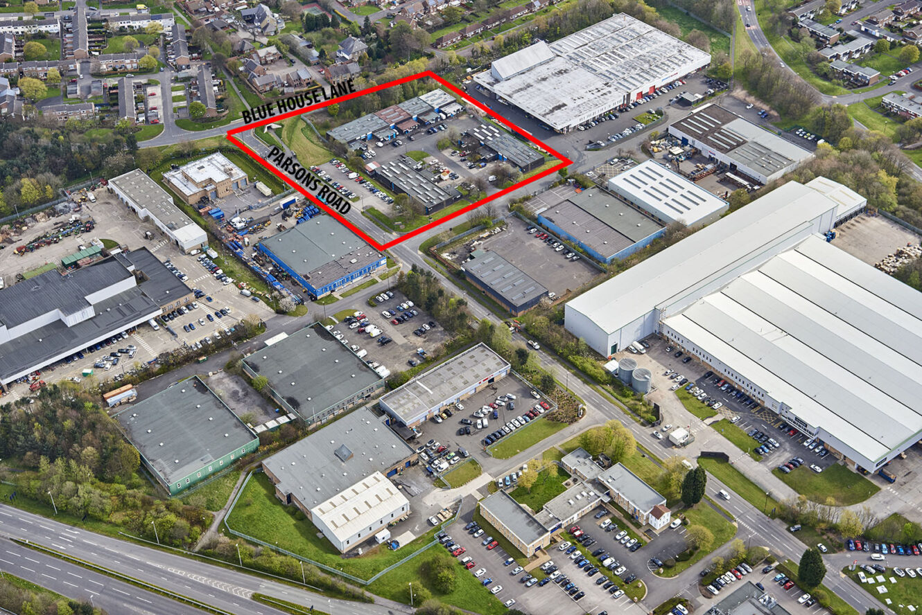 Aerial view of an industrial estate with buildings, parking lots, and roads. An area is outlined in red and labeled Blue House Lane and Parson’s Road.