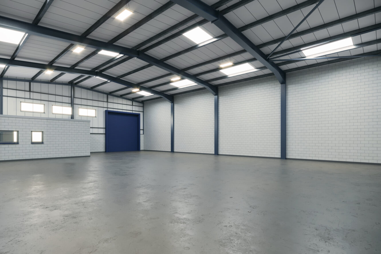 Empty warehouse interior with white brick walls, a polished concrete floor, exposed steel beams, skylights, a blue industrial door, and small windows in one corner.