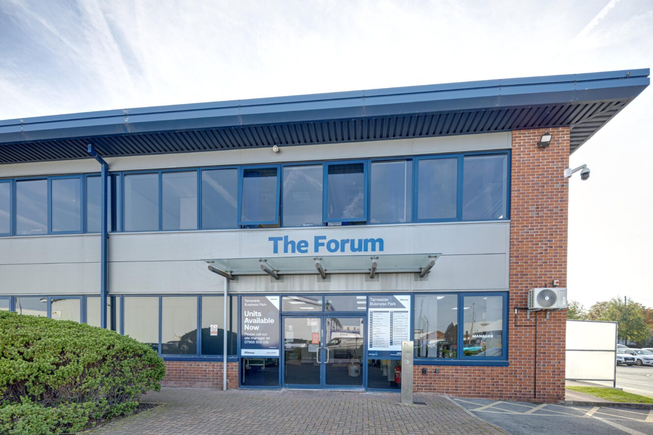 Front view of a modern two-story office building with “The Forum” sign above the entrance and large windows on both floors.