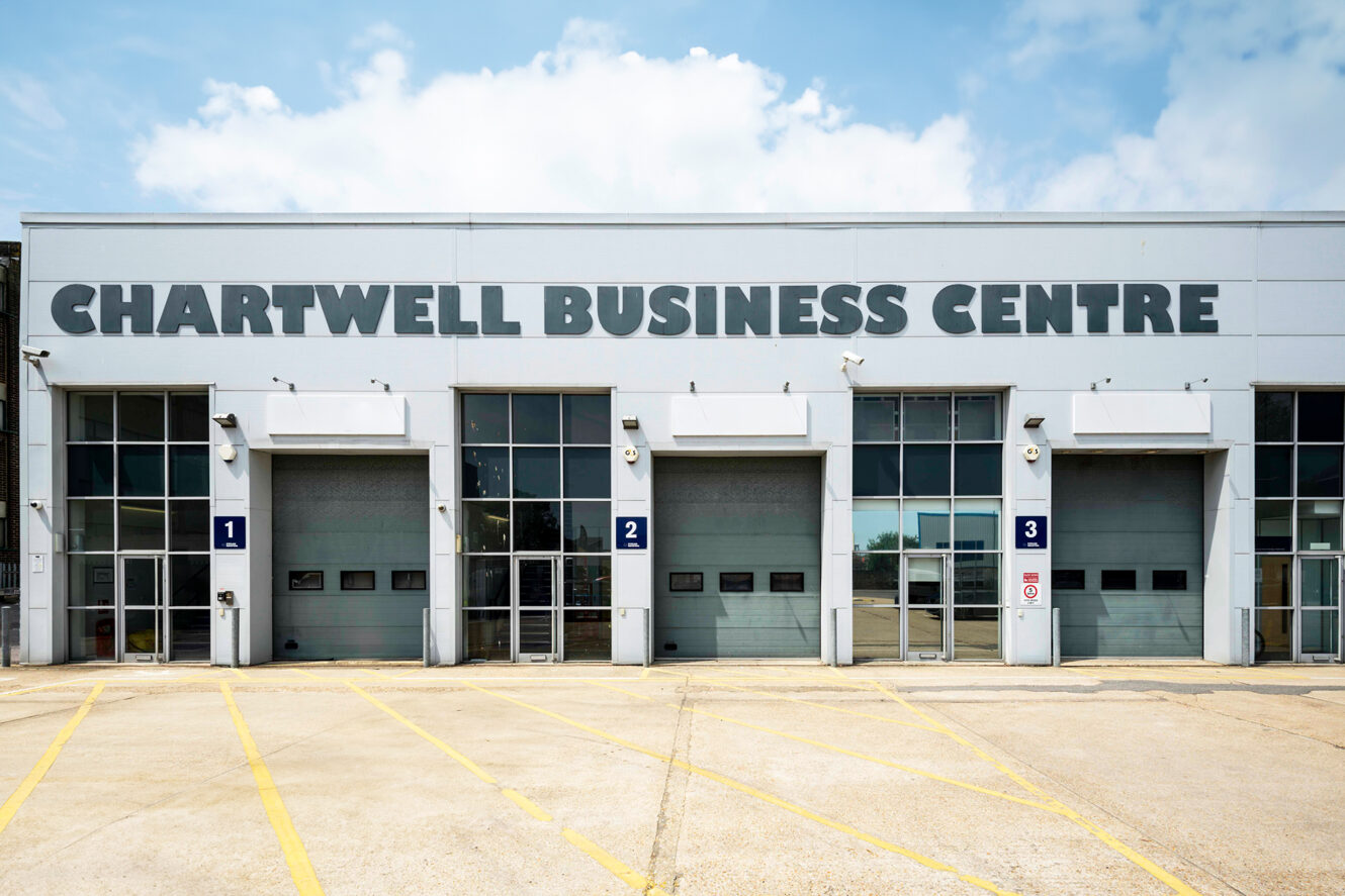 Chartwell Business Centre building with four large garage doors, numbered 1 to 4, and glass entrance panels, seen on a clear day.