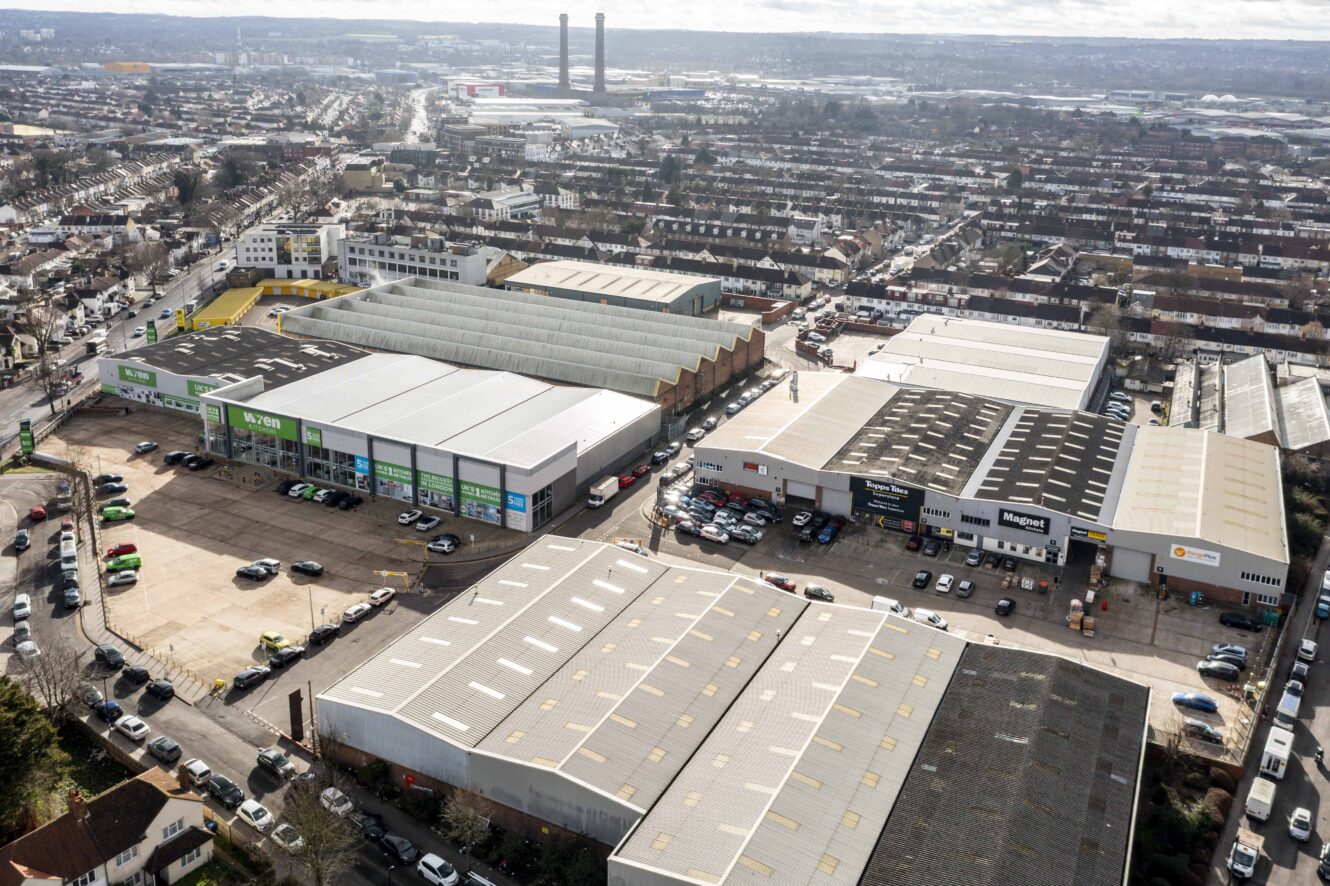 Aerial view of a commercial and industrial estate with large warehouse buildings, parking lots, and surrounding residential neighborhoods.