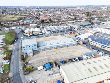 Aerial view of an industrial area with warehouses, factories, and parking lots, surrounded by roads and residential neighborhoods in the background.