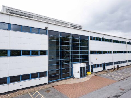 Modern white commercial building with large glass windows, accessible entrance, and adjacent parking spaces, including designated accessible parking spots.