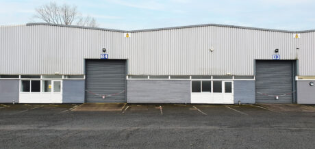 Two industrial warehouse units with closed roller shutters labeled B3 and B4, each with glass doors and windows, and empty parking spaces in front.