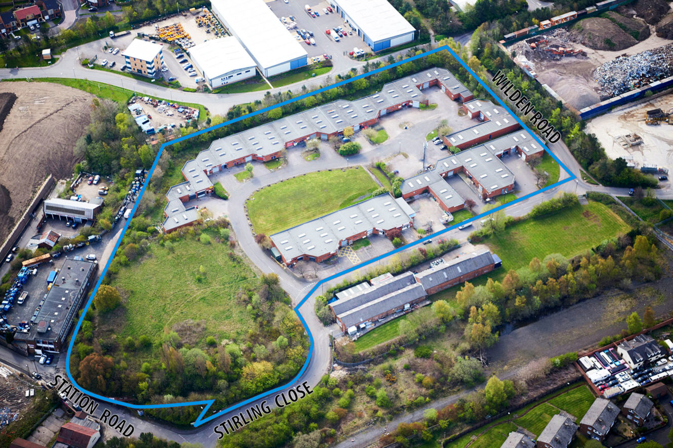 Aerial view of an industrial complex bordered by Station Road, Stirling Close, and Milton Road, with buildings, roads, parking areas, and surrounding green spaces.