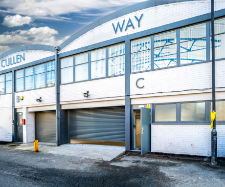 Exterior of a white industrial building with CULLEN WAY signage, two closed roller doors, and a gray door labeled C under a partly cloudy sky.