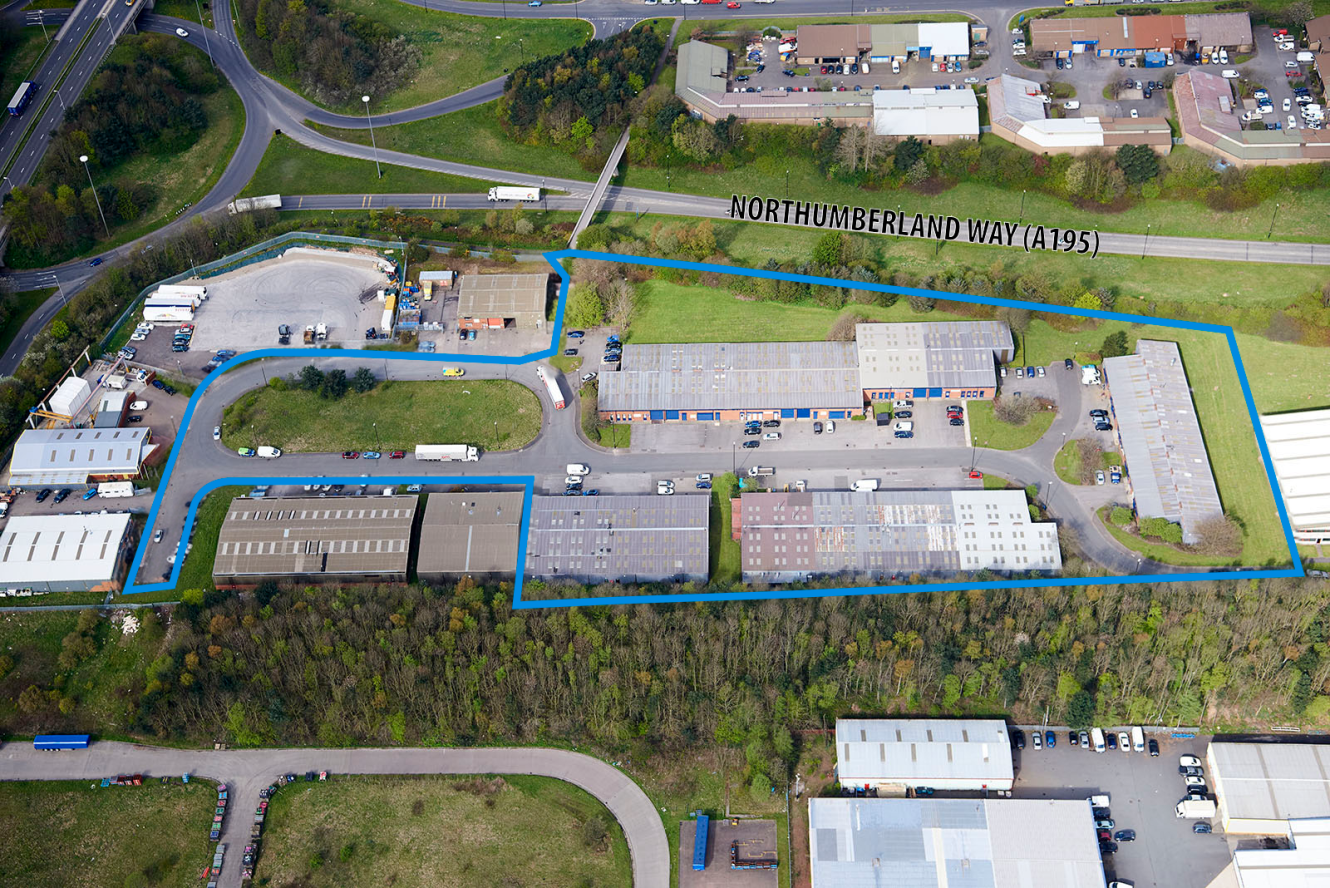 Aerial view of an industrial complex outlined in blue, showing multiple buildings, car parks, and surrounding greenery near Northumberland Way (A195).