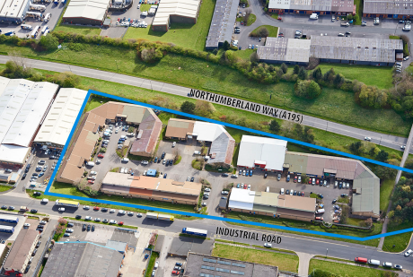 Aerial view of an industrial estate outlined in blue, bordered by Northumberland Way (A195) and Industrial Road, with multiple buildings and parked vehicles visible.