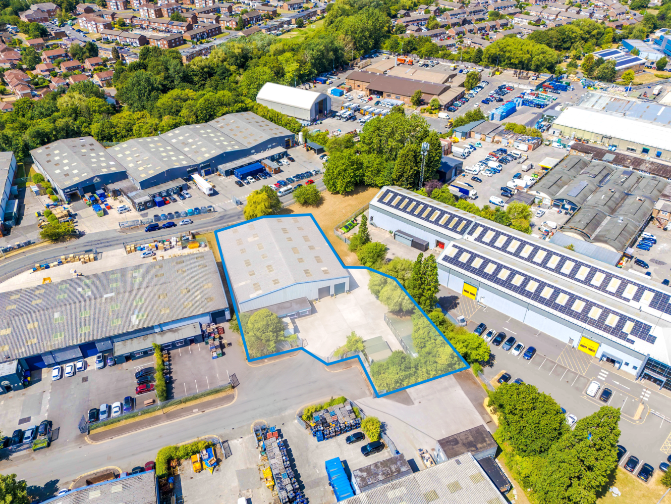 Aerial view of an industrial complex featuring multiple warehouses, with one building and its surrounding area outlined in blue.