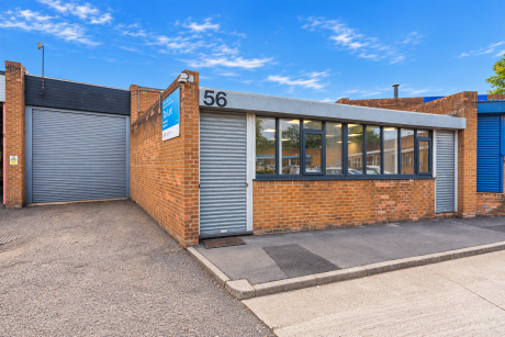 Commercial unit number 56 with a roller shutter door, a row of windows, and a To Let sign on a brick exterior.