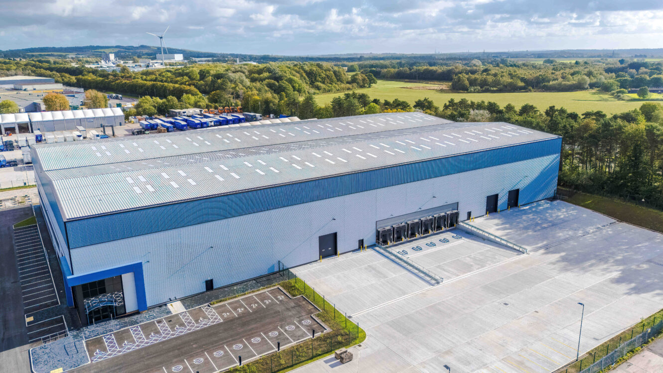 Aerial view of a large warehouse with a gated car park and multiple loading bays.