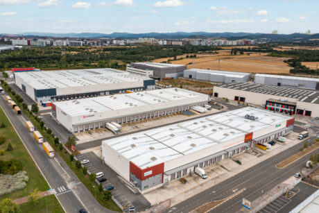Vista aérea de un gran polígono industrial con múltiples edificios de almacenes, muelles de carga, camiones aparcados y carreteras circundantes.