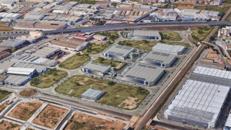 Vista aérea de un polígono industrial con varios grandes almacenes, carreteras circundantes, zonas verdes y edificios comerciales adyacentes.