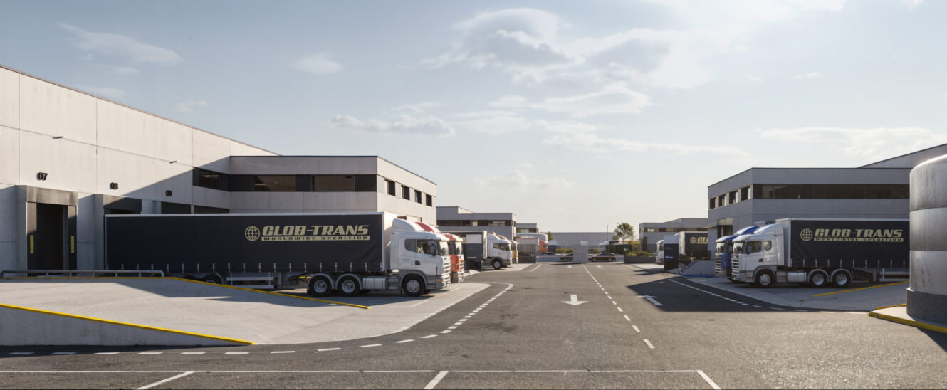 En un día despejado, varios semirremolques están aparcados en el exterior de grandes almacenes, con los logotipos de Glob-Trans visibles en los remolques.