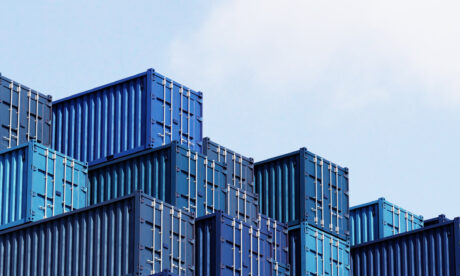Contenedores azules apilados en un cielo parcialmente nublado.