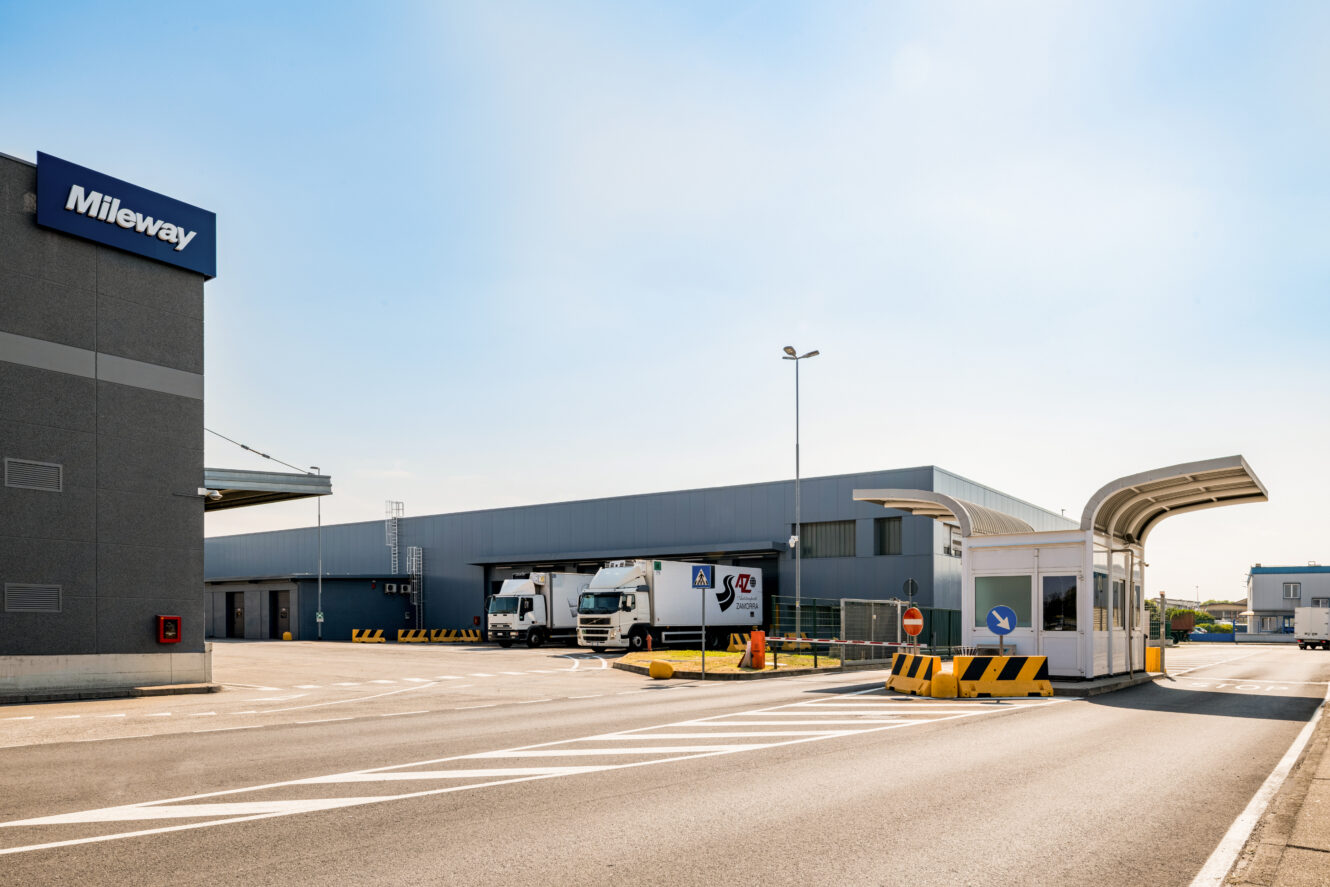 I camion sono parcheggiati all'esterno di un grande complesso industriale con una cabina di sicurezza all'ingresso.