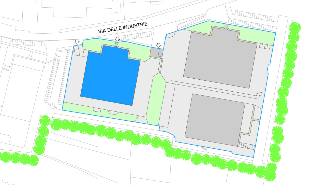 Pianta del sito che mostra tre grandi edifici, uno evidenziato in blu, con aree verdi circostanti, strade, parcheggi e bordi alberati. In alto è riportata la dicitura "Via delle Industrie".