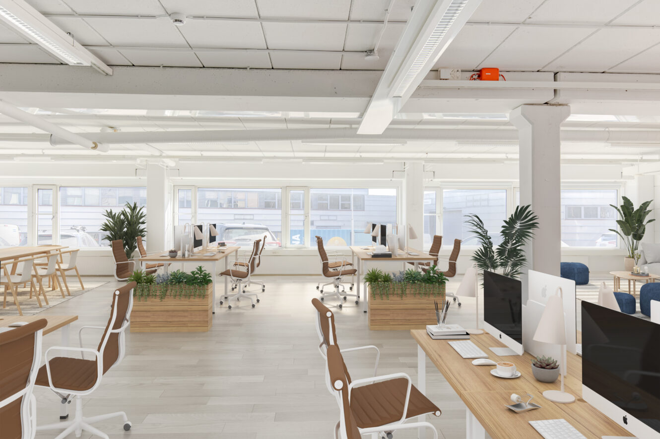 Moderni avotoimisto, jossa on työpöytiä, tietokoneita, valkoisia tuoleja, huonekasveja ja suuret ikkunat, jotka antavat luonnonvaloa.