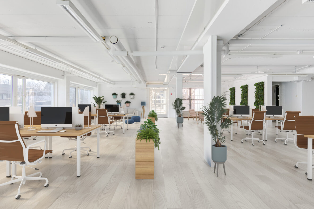 Avoimessa modernissa toimistotilassa on puupöydät, ruskeat tuolit, tietokoneet, suuret ikkunat, huonekasvit ja luonnonvalo.