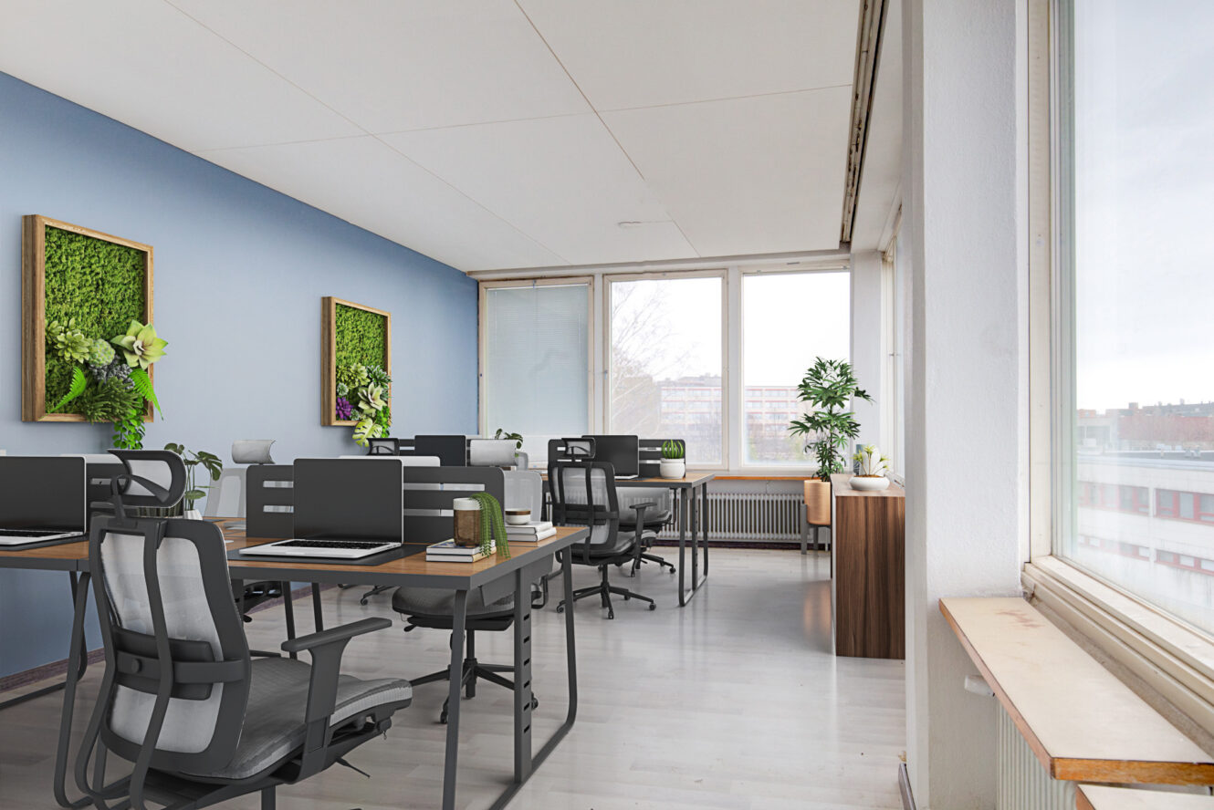 Moderni toimisto, jossa on useita työpöytiä, tuoleja ja tietokoneita; suuret ikkunat päästävät luonnonvaloa sisään, ja huoneen koristeena on viherkasveja.