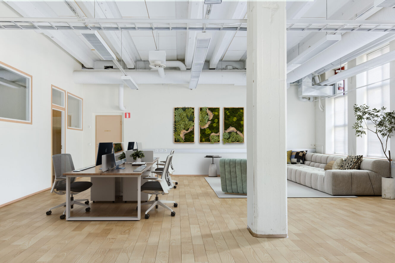 Moderni avotoimisto, jossa vasemmalla puolella on työpöydät, tuolit ja tietokoneet, oikealla puolella oleskelutila, jossa on sohva ja vihreä tuoli, ja suuret ikkunat päästävät luonnonvaloa sisään.