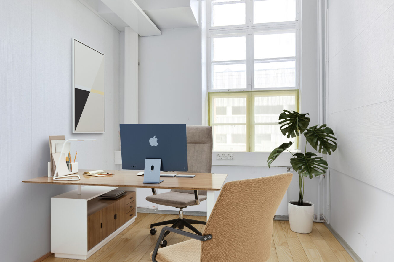 Moderni toimisto, jossa on puinen työpöytä, tietokone, lamppu, muistilappu, ruukkukasvi, beige tuoli ja suuri ikkuna, joka päästää luonnonvaloa sisään.