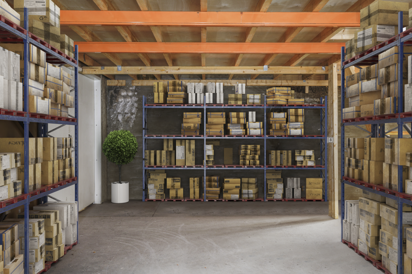 Varaston hyllyt täynnä erikokoisia pahvilaatikoita, ja takaseinää vasten on ruukkukasvi.