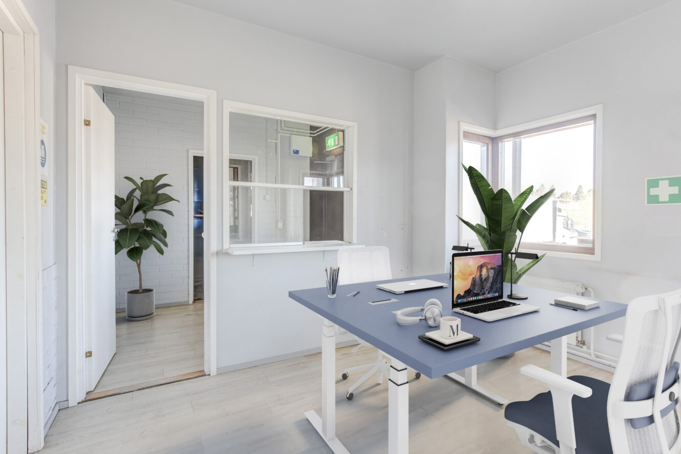 Moderni toimisto, jossa on kaksi työpöytää, toimistotuoleja, kannettavat tietokoneet, paperitavarat, kaksi suurta kasvia ja ikkuna, josta tulee luonnonvaloa.