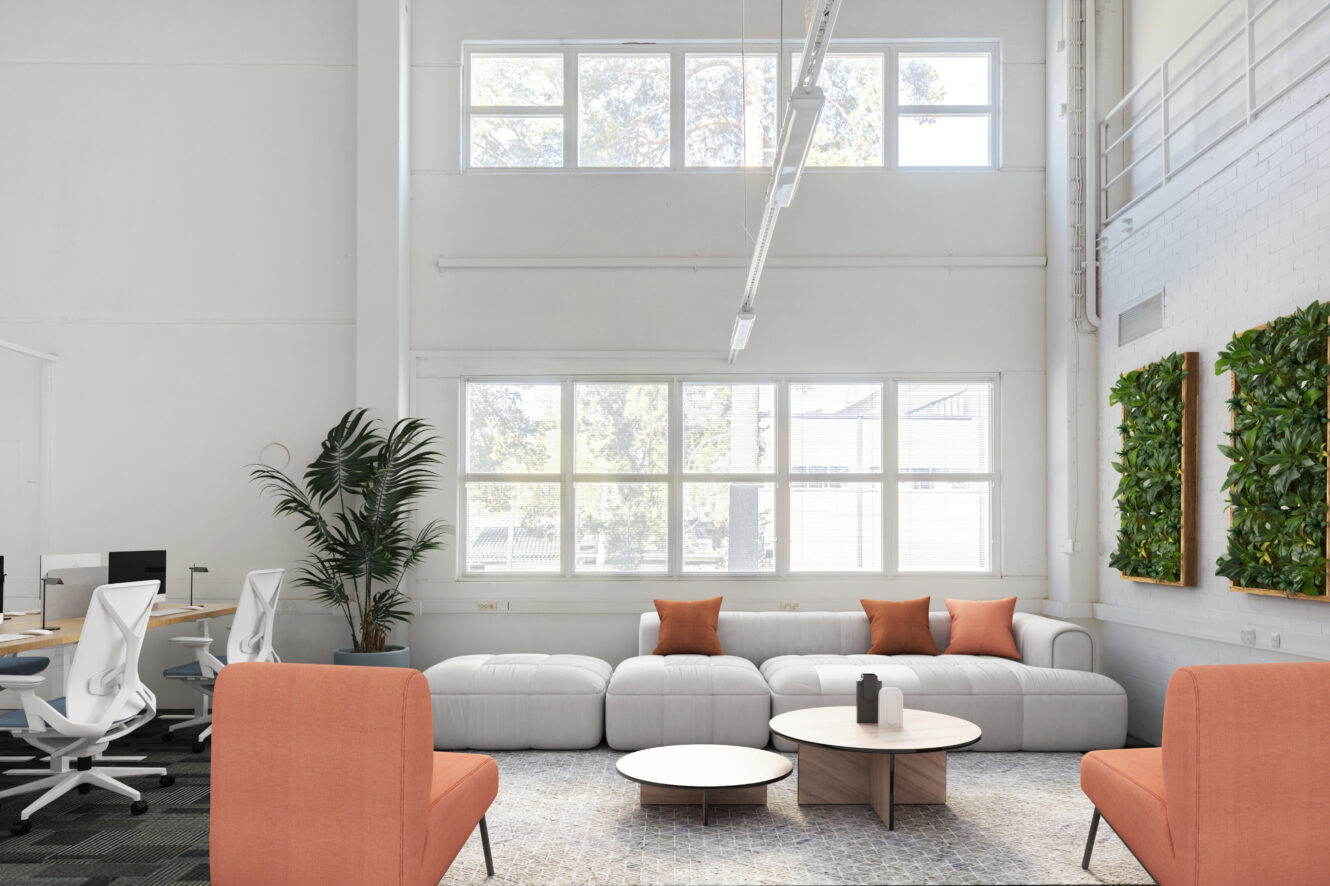 Moderni toimiston oleskelutila, jossa on harmaa sohva, oranssit tuolit, pyöreät sohvapöydät, seinäkasvit ja suuret ikkunat, jotka päästävät luonnonvaloa sisään.
