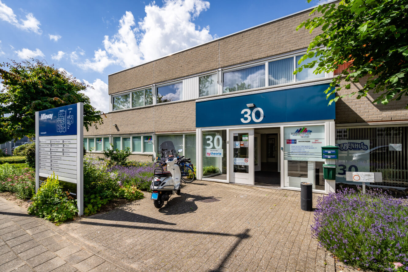 Een modern kantoorgebouw van twee verdiepingen met het nummer 30 boven de ingang, een scooter die buiten geparkeerd staat en een bord met bedrijven aan de voorkant.