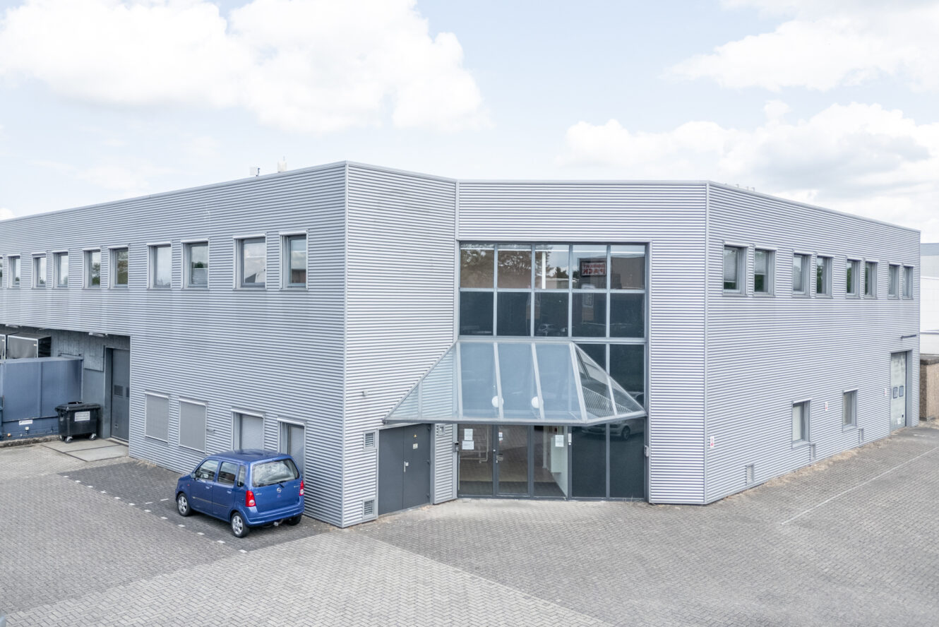 Een blauwe auto geparkeerd bij een gebouw.