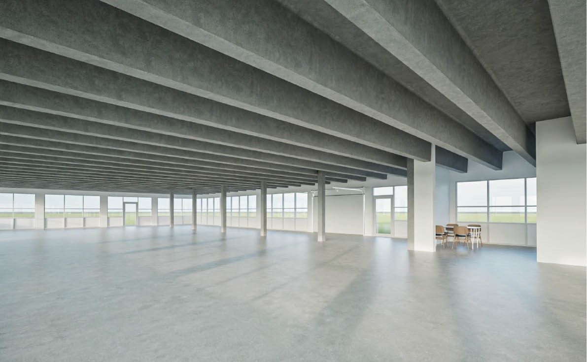 Et stort, tomt rum med synlige loftsbjælker, betongulv og mange vinduer; et lille bord med fire stole er placeret i det ene hjørne.