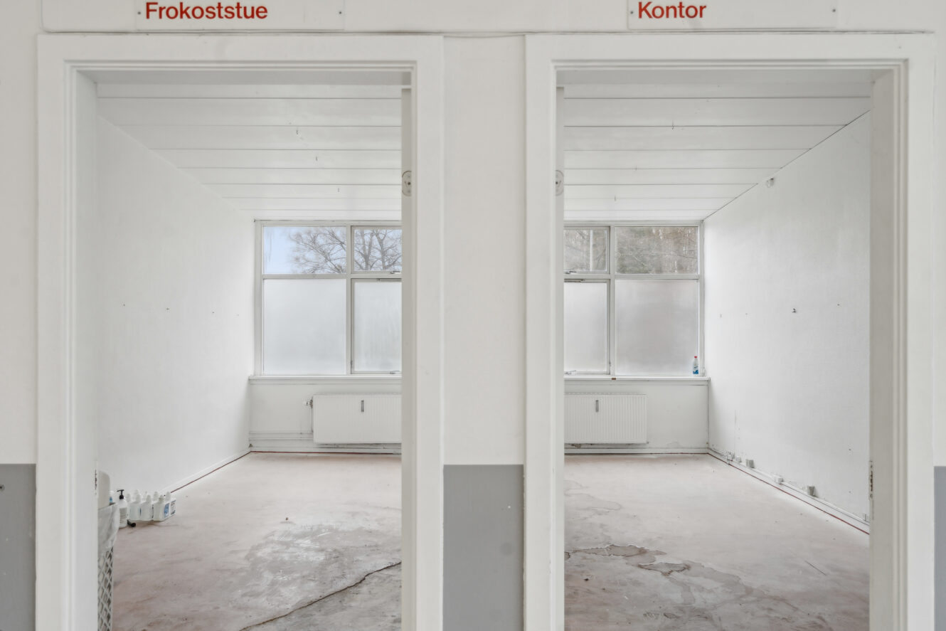 To tomme, umøblerede rum med betegnelserne Frokoststue og Kontor med store vinduer og almindelige hvide vægge.