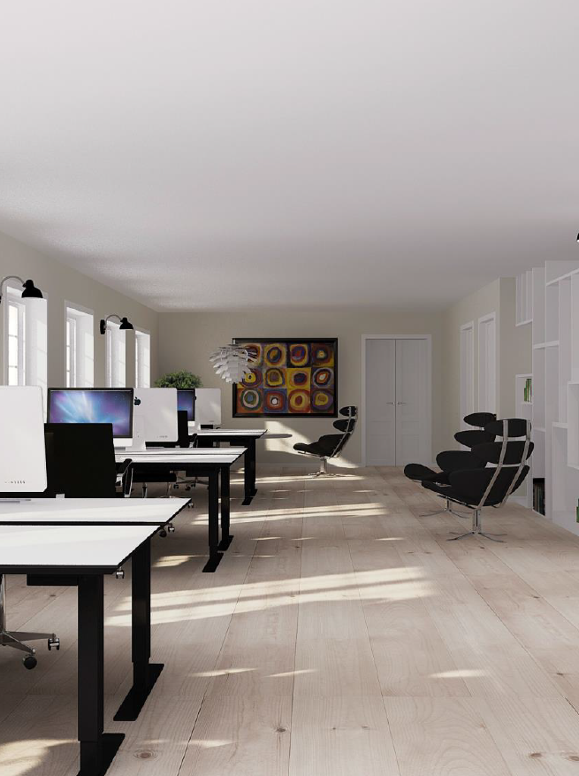 Moderne kontor med hvide skriveborde, computere, sorte stole, lyst trægulv og vægkunst i baggrunden; vinduer langs den venstre væg og hylder til højre.