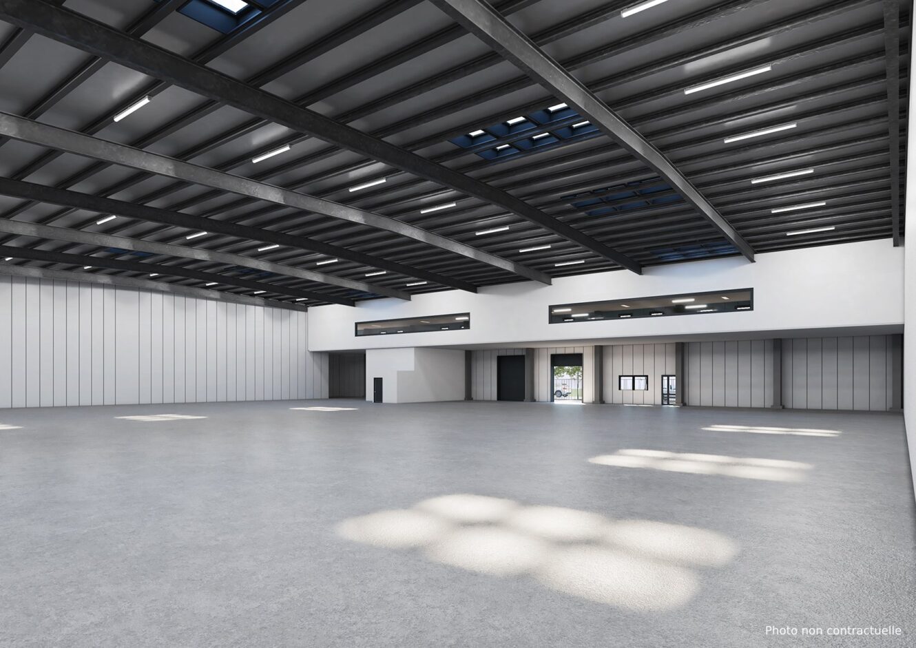 Spacieux entrepôt vide avec de hauts plafonds, des poutres métalliques, de grandes fenêtres et un sol en béton poli, éclairé par la lumière naturelle et artificielle.