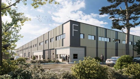 Bâtiment industriel moderne étiqueté "F" avec des voitures en stationnement, des personnes près des entrées et de la verdure au premier plan sous un ciel partiellement nuageux.