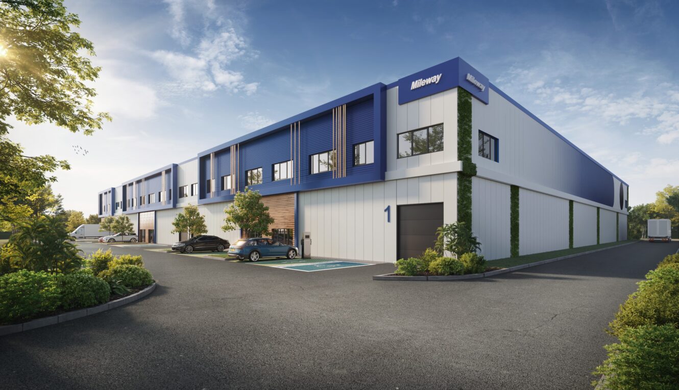 Un entrepôt industriel moderne à l'extérieur bleu et blanc, étiqueté 1, avec des voitures garées et de la verdure autour du bâtiment sous un ciel clair.