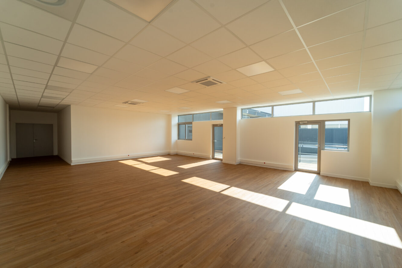 Une pièce avec un plancher en bois et des fenêtres.