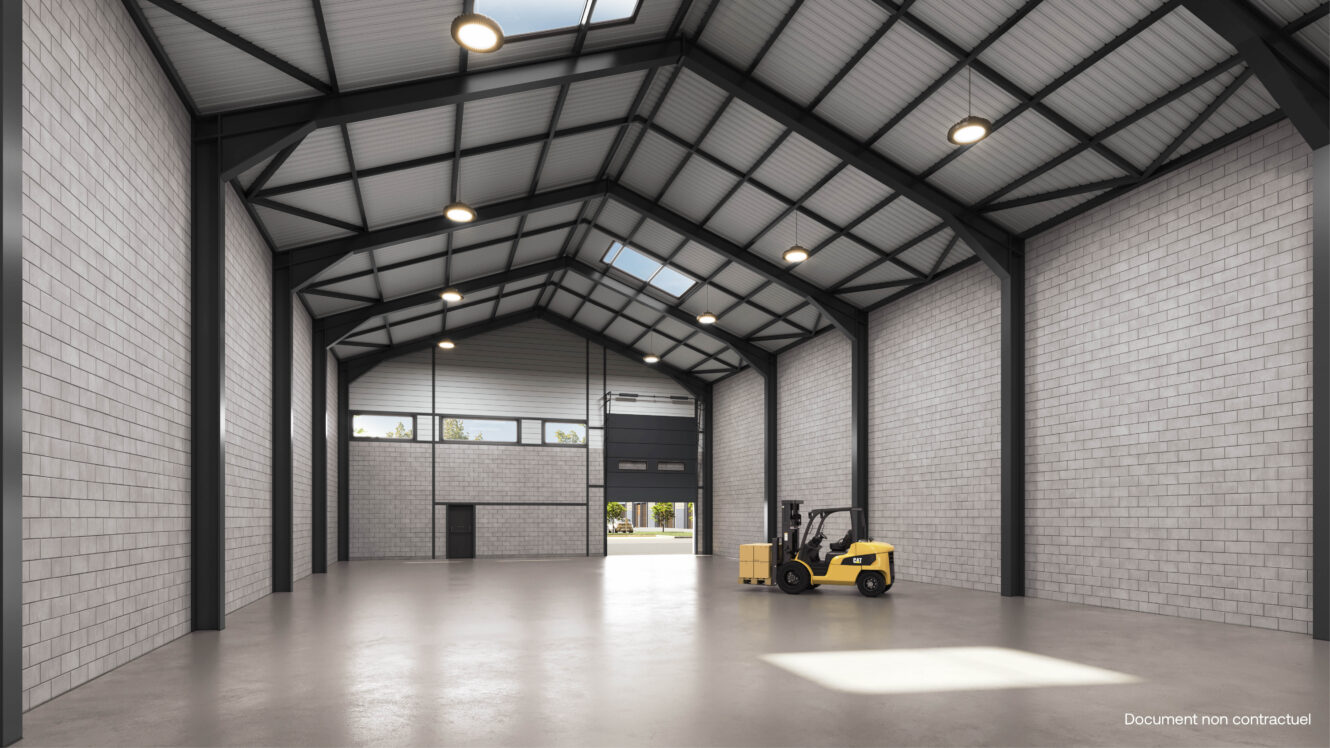 Intérieur d'un entrepôt vide avec de hauts plafonds, des murs en béton, de grandes fenêtres et un chariot élévateur jaune garé près du mur de droite.