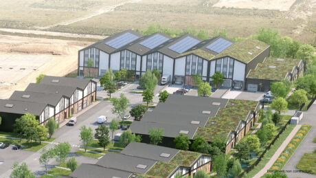 Vue aérienne d'un complexe industriel moderne comprenant plusieurs bâtiments d'entreposage, des panneaux solaires sur les toits, des toits verts, des véhicules en stationnement et de la verdure environnante.