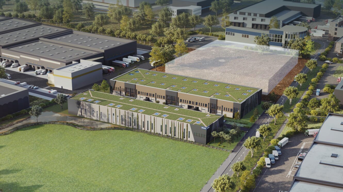 Vue aérienne de deux bâtiments rectangulaires modernes avec des toits verts, entourés d'herbe, d'arbres et de parkings.