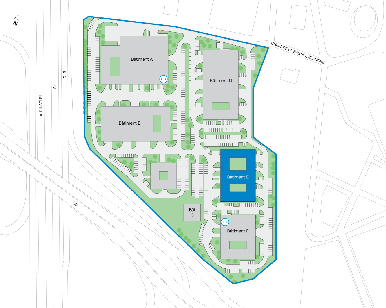 Plan du site présentant six bâtiments identifiés par les lettres A à F, ainsi que les parkings environnants, les voies de circulation internes et les espaces verts. Le bâtiment E est mis en évidence en bleu, près du centre-droit du plan.