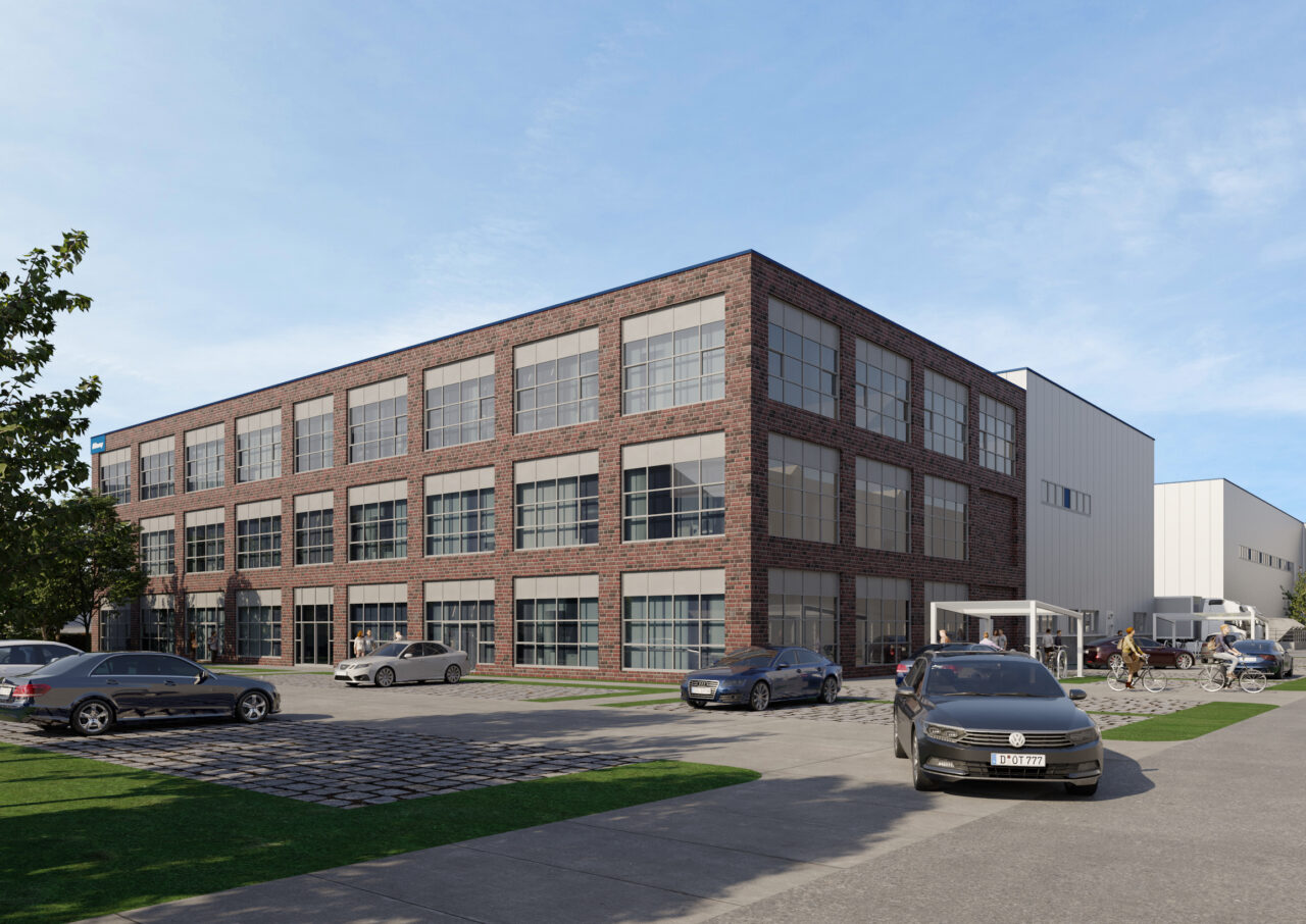 Ein dreistöckiges Bürogebäude aus Ziegeln und Glas mit geparkten Autos und Fahrrädern unter freiem Himmel.