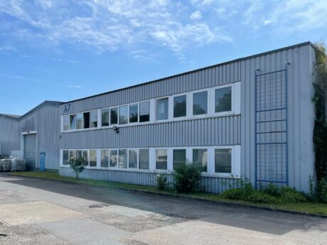 Ein zweistöckiges Industriegebäude mit mehreren Fenstern und Wellblechverkleidung mit der Bezeichnung A7 unter blauem Himmel.