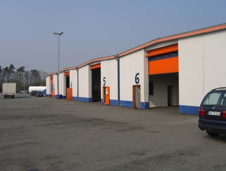 Eine Reihe von Industriehallen mit den Nummern 3 bis 6 und offenen, orangefarbenen Ladetoren.