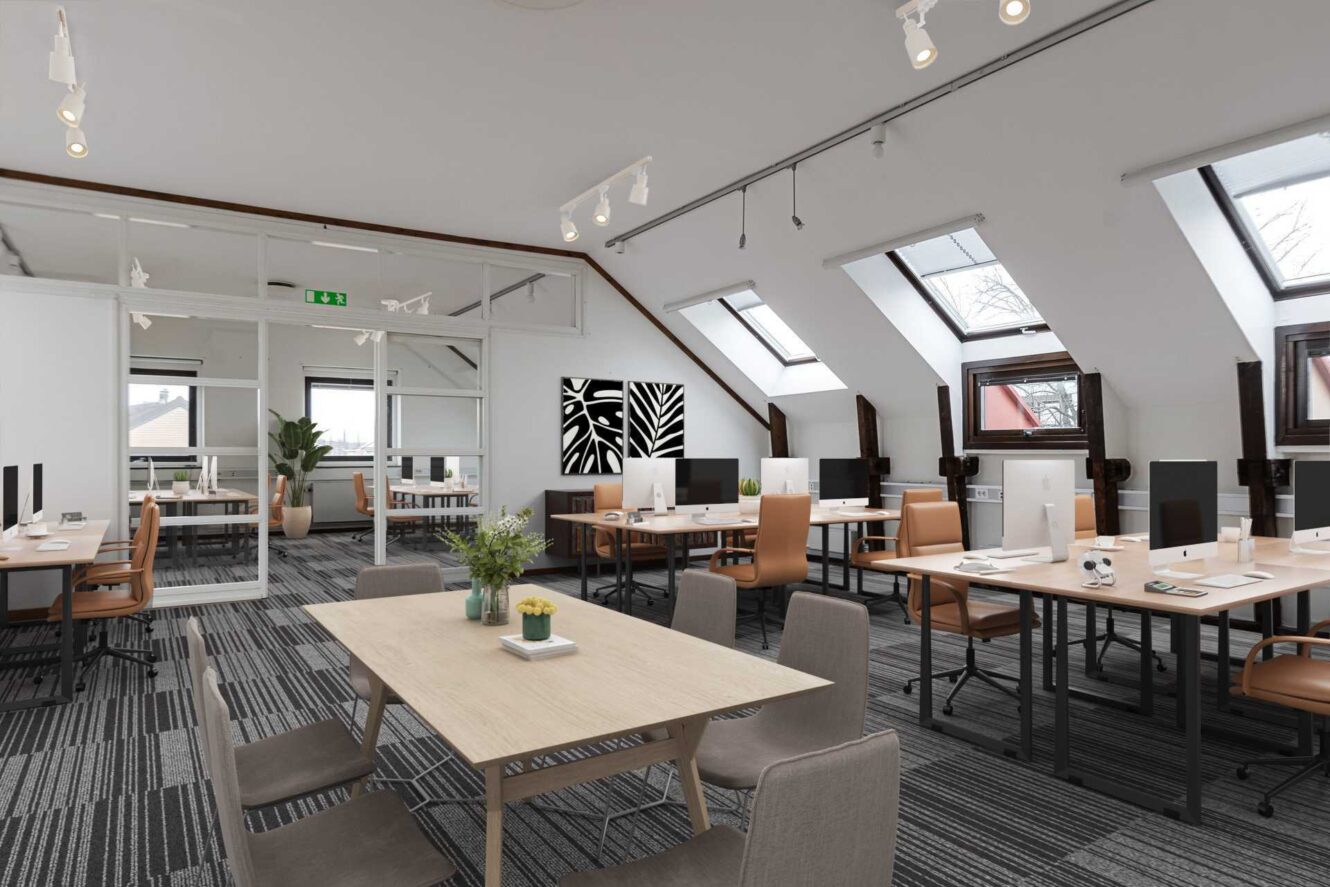 Modernt öppet kontorslandskap med skrivbord, datorer, kontorsstolar, ett centralt mötesbord, stora fönster, snedtak och ett svartvitt abstrakt konstverk på väggen.