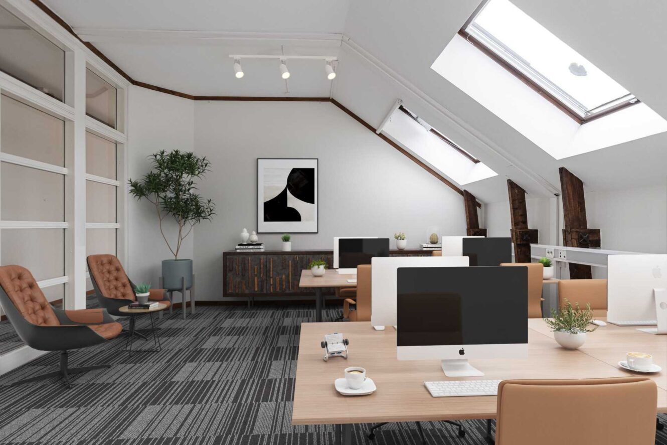 Modernt kontor med rader av träskrivbord, datorer, en sittgrupp, stora fönster, takfönster, en krukväxt och minimalistisk inredning.