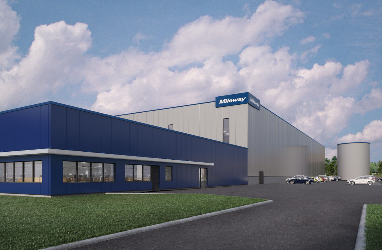 En stor, modern industribyggnad med blå accenter, märkt "Mileway", står nära en parkeringsplats med flera bilar under en delvis molnig himmel.