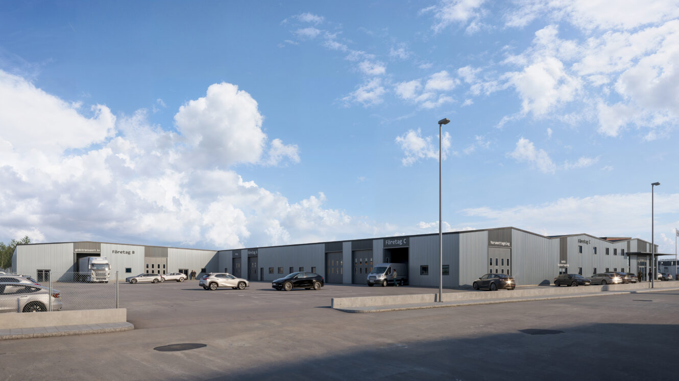 En vid vy över ett modernt industrikomplex med flera grå lagerbyggnader, parkerade bilar och en klarblå himmel med spridda moln.